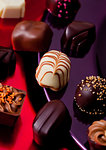 Assortment of luxury white and dark chocolate candies variety on red and violet plate