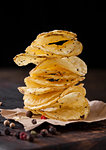 Crispy delicious pepper potato crisps chips snack on dark wooden board and brown paper