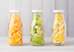 Bottles of fresh summer water with oranges with limes and lemons slices on wooden background