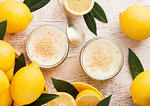 Glass jar with lemon cheesecake with fresh lemons on wooden background