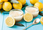 Glass jar with lemon cheesecake with fresh lemons on bluw wooden background