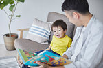 Japanese father and kid reading on the sofa