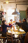 Young adult friends toasting cocktails at apartment kitchen table