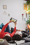 Young couple relaxing, using digital tablet on bed