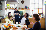 Young adult roommate friends talking at breakfast table in apartment