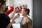 Young women friends getting ready, putting on makeup in bathroom