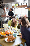 Young college student roommates talking at kitchen table in apartment