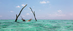 Young woman laying in hammock over tranquil blue ocean, Maldives, Indian Ocean