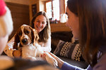 Mother and daughter playing with dog in living room