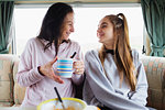 Happy mother and daughter enjoying hot chocolate in motor home