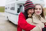 Affectionate mother and daughter in warm clothing hugging outside motor home