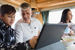 Father and son using digital tablet in motor home