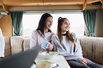 Happy mother and daughter enjoying breakfast in motor home