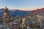 Cairns on summit of Petersköpfl with Lake Schlegeispeicher and Hochfeiler group on the background, Zillertal Alps, Tyrol, Schwaz district, Austria.