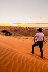 Tourist admiring the sunset over the rippling red dunes,Namib Naukluft National Park,Namibia,Africa