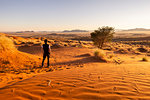 Tourist admiring the sunrise over the rippling red dunes,Namib Naukluft National Park,Namibia,Africa