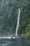 Touristic boat and Stirling Falls in Milford Sound. Fiordland NP, Southland district, Southland region, South Island, New Zealand.