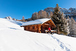 a hiker is relaxing on the snow in front of a mountain hut in Val Gardena, Bolzano province, South Tyrol, Trentino Alto Adige, Italy