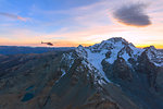 Aerial view of helicopter in flight on Monte Disgrazia at sunset, Valmalenco, Val Masino, Valtellina, Lombardy, Italy