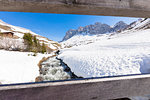 Torrent surrounded by snow seen from wooden fence, Partnun, Prattigau, Davos, canton of Graubunden, Switzerland