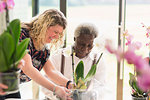 Female instructor helping active senior man in flower arranging class