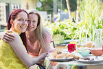 Portrait affectionate lesbian couple enjoying lunch on patio