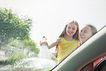 Mother and daughter washing car windshield