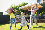 Lesbian couple and daughter playing with plastic hoops in sunny backyard