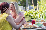 Affectionate lesbian couple enjoying lunch at patio table