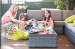 Lesbian couple enjoying white wine and doing craft project with daughter on patio