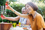 Happy active senior women toasting rose wine at garden party