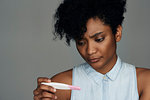 Close-up of young woman looking at pregnancy test strip