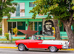 An old American car driving past a mural of Che Guevara, in Varadero, Cuba, West Indies, Central America