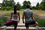 Man and woman practicing yoga in garden, rear view of tree pose