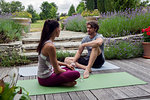 Man and woman practicing yoga in garden, taking a break on patio