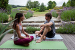 Man and woman practicing yoga in garden, taking a break on patio