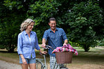 Mature couple pushing bicycle on rural road