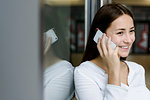 Woman leaning on glass wall using cellphone