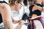 Tattooist attending to customer in parlour