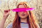 Girl obscuring eyes with pink feather