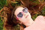Girl with heart shaped sunglasses lying on grass