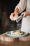 Potato gnocchi on plate being garnished