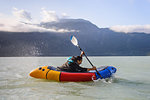 Woman packrafting, Howe Sound bay, Squamish, Canada