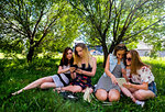 Girlfriends relaxing, using smart devices in city park