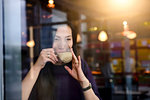 Mid adult woman drinking coffee in cafe window seat