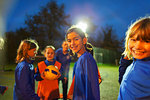 Portrait smiling girls soccer team on field at night