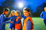 Portrait confident girl soccer player on field with team at night