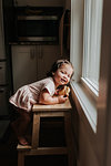 Girl leaning on ladder by window