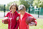 Active senior women friends playing basketball in sunny park