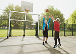 Active senior men friends playing basketball in sunny park